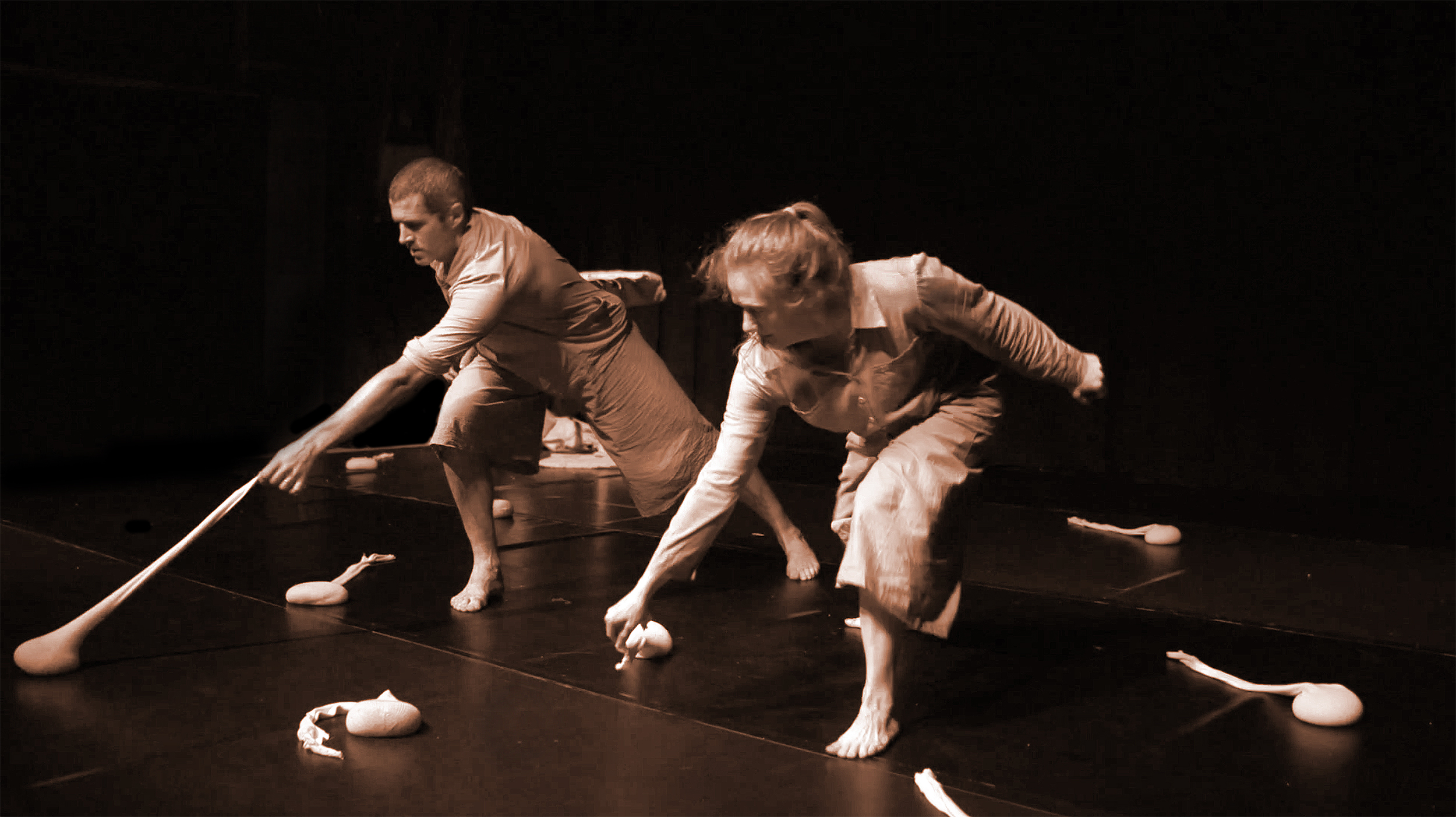 two dancers on stage manipulating sandbag-like props